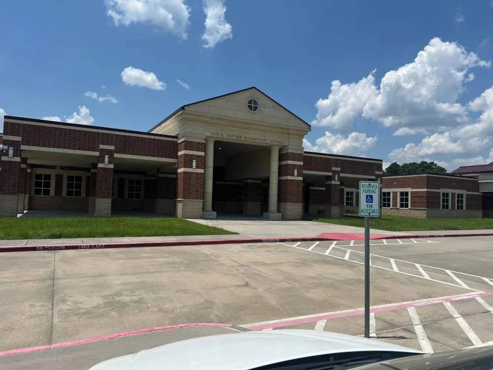 Front view of a red-brick elementary school building under a clear blue sky.