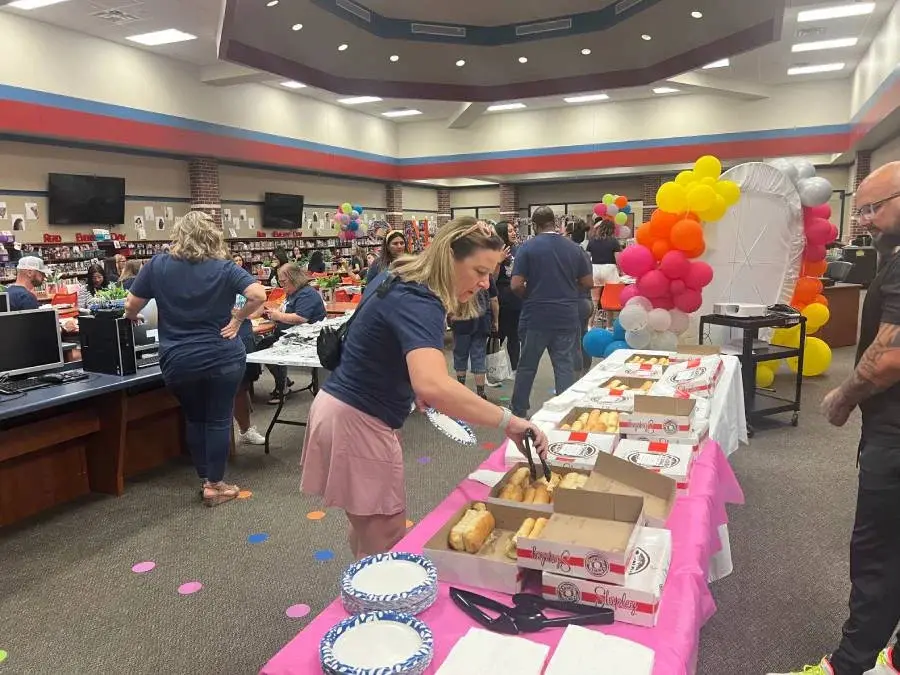 Guests enjoying food and activities during a community gathering at a school library.