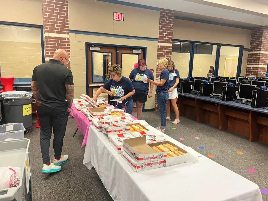 Volunteers serving food at an event in a school computer lab setting.
